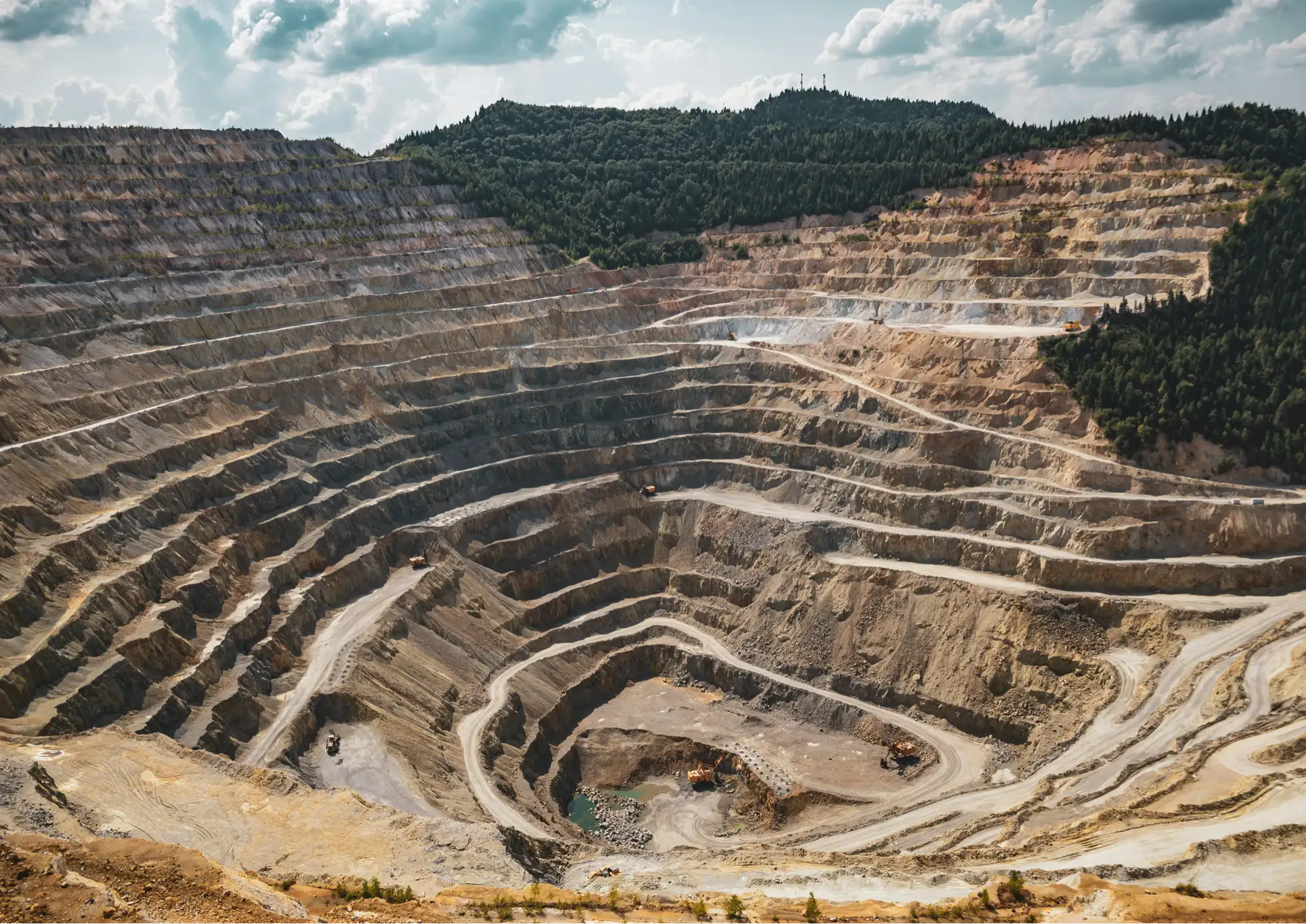 Aerial view of an open-pit mine surrounded by forest